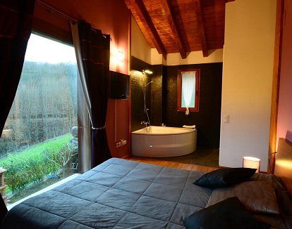 Alojamiento vacacional con chimenea y una habitación con jacuzzi junto a la cama y con vistas al campo