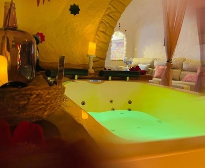 Jacuzzi con velas en los lados y con el sofa al fondo en la Suite con Bañera de hidromasaje