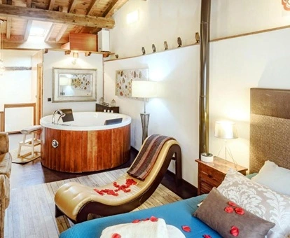 Foto de la cama, el sillon tanta y el jacuzzi en el dormitorio de la casa rural El Naturalista en Casas del Abad