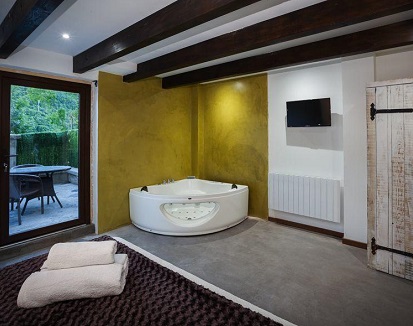 Habitación triple deluxe con terraza y jacuzzi junto a la cama en hotel rural Albergue Boi Romanic Suites