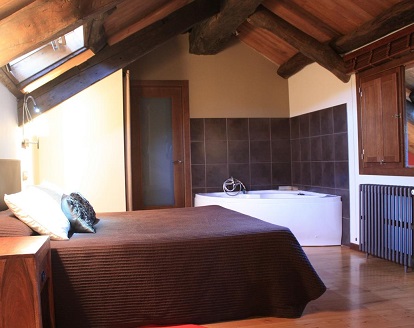 Foto de la habitación doble superior con bañera de hidromasaje junto a la cama en un hotel rural con mucho encanto en la población de Rocha en la provincia de Lugo
