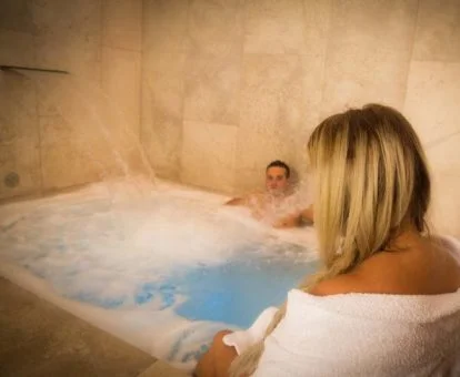 Pareja disfrutando de la zona de aguas del centro de spa del hotel.