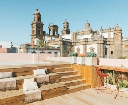 Terraza solarium con mobiliario al aire libre, piscina y vistas a la catedral.