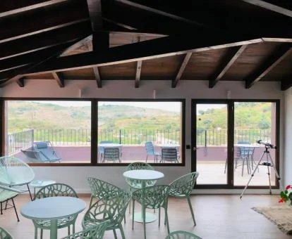 Comedor interior con acceso a una terraza amueblada y vistas al campo que rodea al hotel.