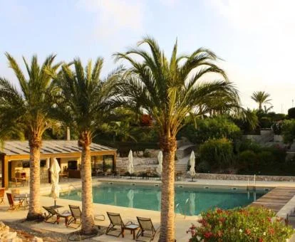 Zona exterior con piscina y mobiliario rodeada de vegetación de este hotel rural.