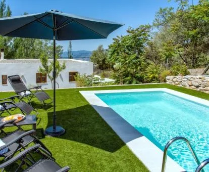 Agradable zona exterior con piscina al aire libre y solarium de esta casa independiente. 