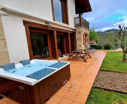 Zona exterior ajardinada con jacuzzi privado y vistas de uno de los apartamentos del establecimiento.