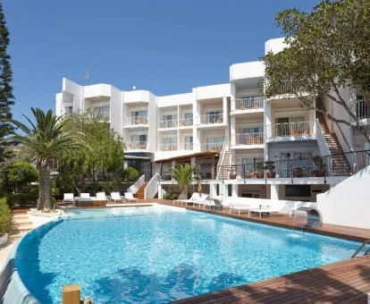 Edificio de este complejo de apartamentos con piscina y tumbonas.