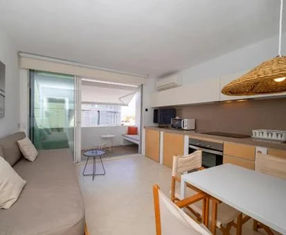 Interior de uno de los coquetos apartamentos de este complejo con sofá, cocina completa, comedor interior y terraza.