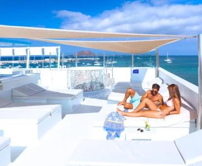 Pareja disfrutando de una de las cómodas tumbonas de la terraza solarium con vistas al mar del hotel.