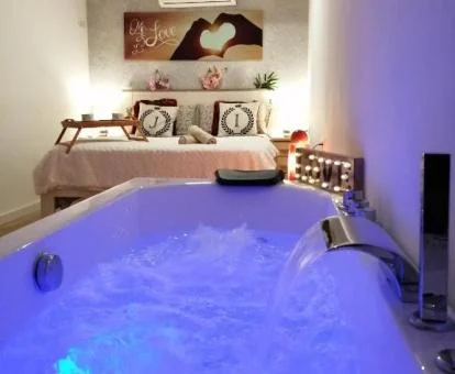 Precioso jacuzzi privado con chorro en cascada junto a la cama de uno de los apartamentos del establecimiento.