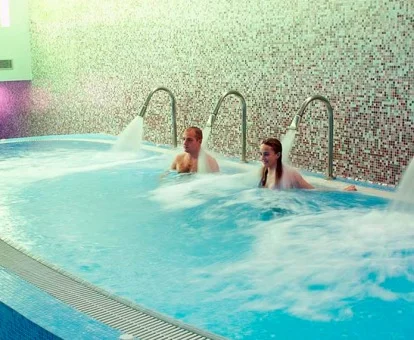 Pareja disfrutando de la piscina de hidroterapia del spa.