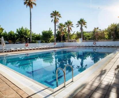 Amplia piscina rodeada de vegetación de este camping cerca de la playa.
