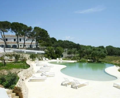 Hotel con encanto rodeado de vegetación con una gran piscina en forma de laguna.