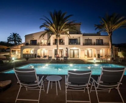 Hermoso hotel rural con iluminación nocturna y piscina exterior con solarium.