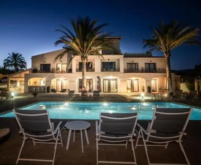 Precioso hotel rural con iluminación nocturna y piscina exterior.