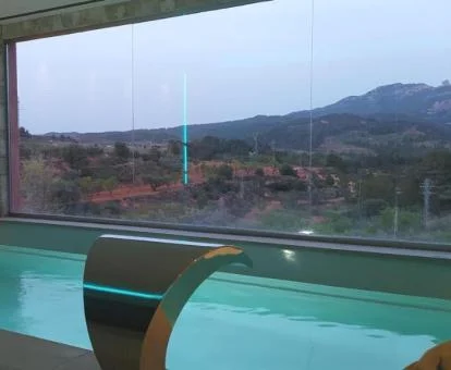 Piscina con chorros en cascada y vistas a la naturaleza de la zona de bienestar del hotel.