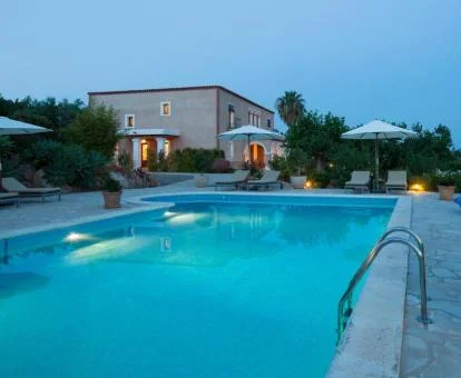 Edificio de este hotel rural con piscina rodeada de vegetación.