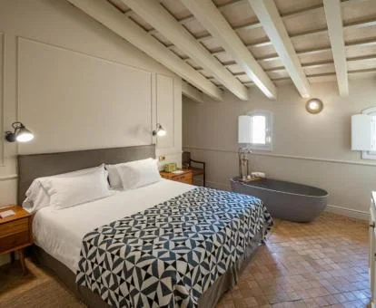 Una de las coquetas habitaciones dobles con bañera junto a la cama del hotel.