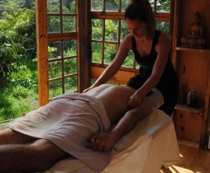 Hombre disfrutando de un masaje en el espacio de relajación con vistas a la naturaleza del establecimiento.