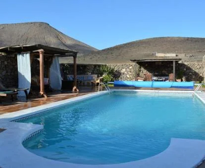 Agradable terraza con mobiliario exterior, piscina y vistas a las montañas de este alojamiento rural.