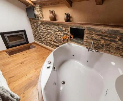 Bañera de hidromasaje privada cerca de la cama de uno de los apartamentos superiores del establecimiento.