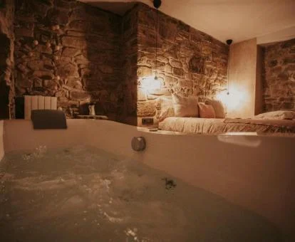 Amplio jacuzzi privado junto a la cama de este apartamento rural.