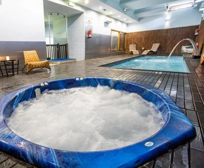 Zona de aguas con piscina cubierta, jacuzzi y zona de relajación del spa.