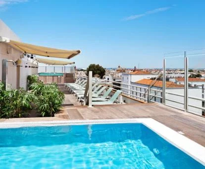Terraza en la azotea con piscina, solarium y vistas a la ciudad de este hotel con encanto.