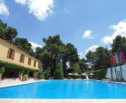 Coqueto hotel rural con amplia piscina exterior rodeada de jardines.