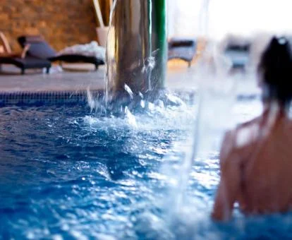 Mujer disfrutando de la piscina de hidroterapia del spa del hotel.