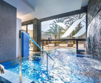 Preciosa piscina interior del spa con elementos de hidroterapia que sale al exterior.