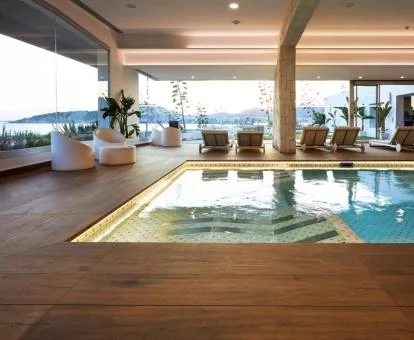 Piscina cubierta del spa con zona de relajación y amplias cristaleras con espectaculares vistas.