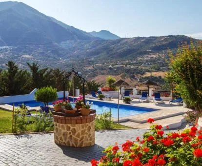 Amplia zona exterior ajardinada con piscina y vistas a las montañas de este cortijo rural.