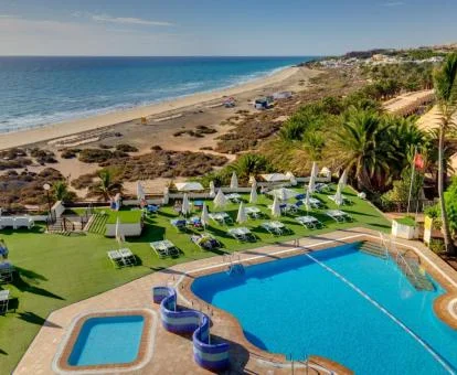 Piscina exterior con vistas al mar, tumbonas y bellos jardines de este hotel solo para adultos.