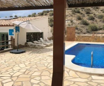 Zona exterior con piscina y mobiliario de este establecimiento rural de cuevas.