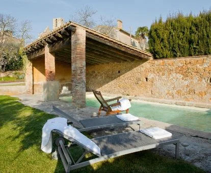Zona exterior con piscina y solarium rodeada de jardines de este hotel rural.
