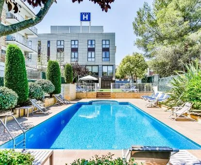 Edificio de este hotel con piscina rodeada de jardines.