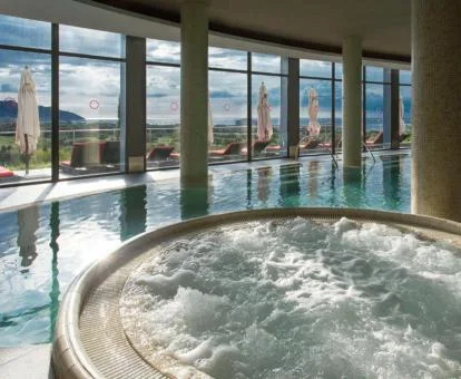 Piscina cubierta con hidroterapia y vistas al exterior del centro de bienestar del hotel.