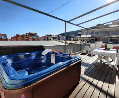 Espectacular terraza con mobiliario al aire libre y un gran jacuzzi privado en el exterior de este ático.