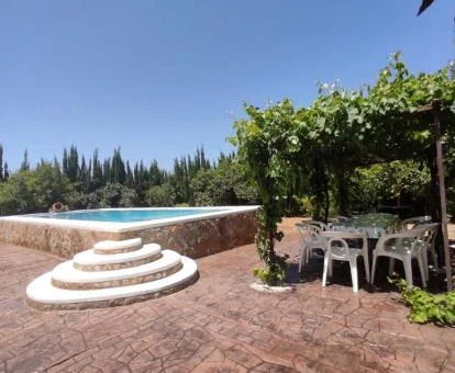 Amplia zona exterior de esta casa con piscina privada rodeada de vegetación.