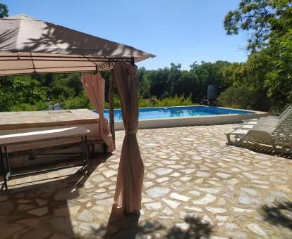 Zona exterior rodeada de naturaleza con piscina y mobiliario de esta casa independiente.