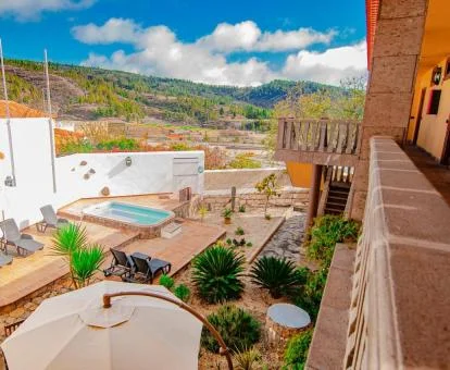 Zona exterior con mobiliario y piscina con vistas a las montañas que rodean el hotel.