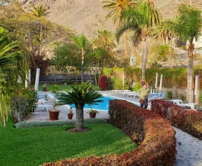 Amplia zona exterior con jardines, piscina al aire libre y vistas a las montañas.