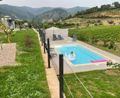 Zona exterior ajardinada con piscina de este hotel rodeado de montañas.