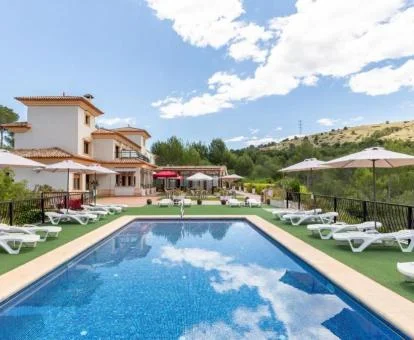 Hotel rural con una amplia piscina exterior con solarium y tumbonas.