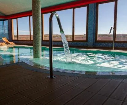 Piscina cubierta con hidroterapia y vistas al exterior del centro de bienestar del hotel.