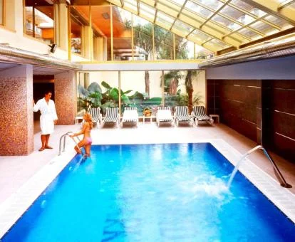 Pareja disfrutando de la piscina con elementos de hidroterapia del hotel.