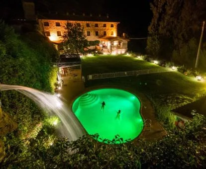 Espectacular hotel rural con piscina y un bello exterior con iluminación nocturna.