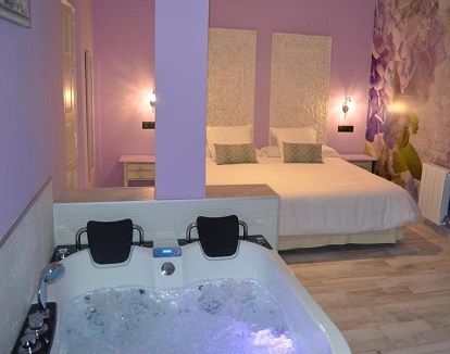 Foto del jacuzzi de gran tamaño junto a la cama ideal para parejas en la habitación doble con cama grande y bañera de hidromasaje.